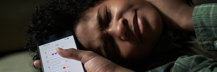 Header of child lying down while crying, holding smartphone, expressing deep sadness. Emotional...