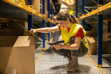 A woman in a yellow vest scans items in a warehouse, highlighting the importance of organization and safety in logistics operations.