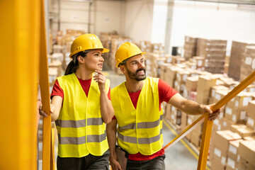Two employees in hard hats share insights while walking through the warehouse, emphasizing teamwork and collaboration in logistics.