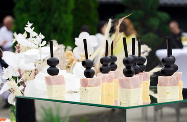 Italian style appetizer,antipasto skewer or caprese on stick with cheese,olives,prosciutto and pear.Beatifully decorated banquet catering table.Corporate birthday party event or wedding celebration.