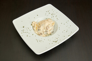 A white plate with a creamy sauce on it. The sauce is on top of a pasta dish