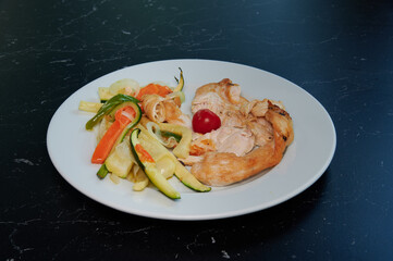 A plate of food with a piece of meat and vegetables. The meat is cut into small pieces and the vegetables are cut into thin strips