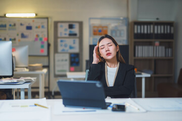 Young professional woman feeling tired and suffering from headache after working on computer in...