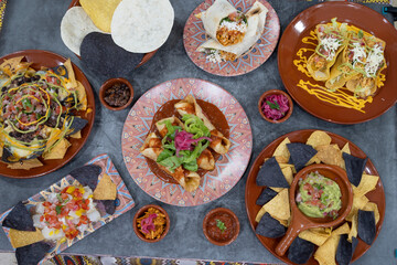 A table with many different types of food, including tacos, enchiladas, and nachos