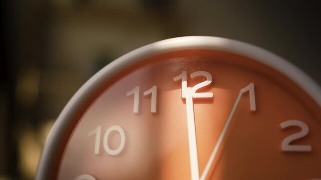 Minimalist analog clock with orange face showing 12.00 or 24.00. Time management