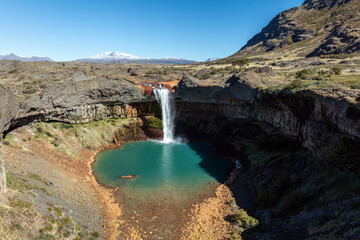 Salto del Agrio waterfall plunges into a turquoise pool surrounded by rocky terrain. Neuquen, Argentina