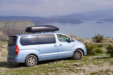 A car with an upper trunk on the background of a river and mountains. Recreation and travel.