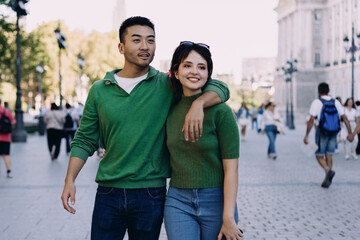 Couple walks close together in historic part of town, chatting and enjoying the sunny day. Their...
