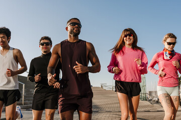 Group of five athletes running and smiling, outdoors
