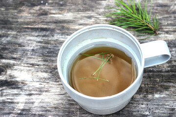tea in a mug on a wooden table, a pine branch lies nearby