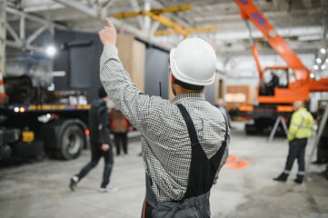 Construction worker directing operations in prefabricated building factory