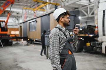 Arab construction worker communicating with walkie talkie during modular house production