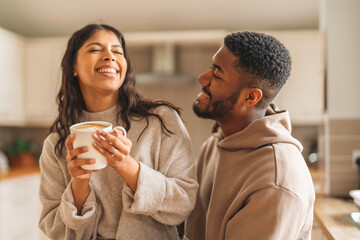 Couple enjoys morning coffee together in a cozy kitchen, sharing smiles and laughter while embracing the start of their day