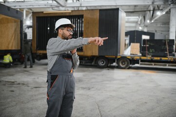 Arab construction worker supervising prefabricated modular house production in workshop