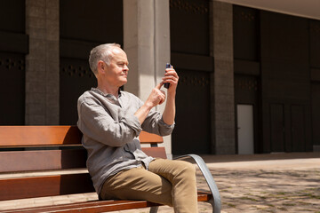 Fototapeta premium Outdoor portrait of man on smartphone. Man over 60 using phone