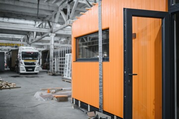 Construction workers building orange prefabricated modular house in workshop