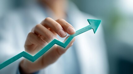 Hand holding teal upward trending arrow - growth and positive trajectory