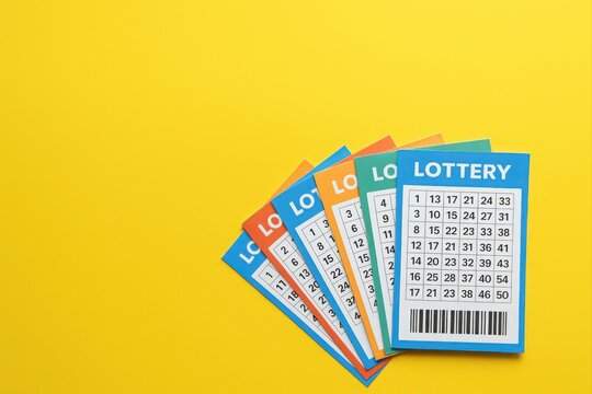 Many colorful lottery tickets are fanned out on a yellow background, suggesting luck, gambling, and the possibility of winning a prize