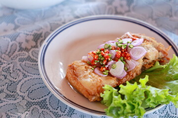 Thai Spicy fermented fish with herbs deep-fry until crispy and add sliced ​​shallots, chopped chili peppers, green salad. Sour fish made from Mrigal carp, Black ear catfish. Spicy fermented fish.
