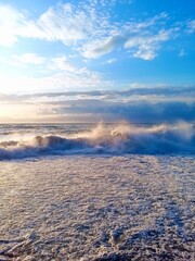 Vertical photo of large waves on the Black Sea at sunset, Batumi, Georgia, dramatic seascape, ocean energy, coastal view, evening light, nature power, sea foam, travel destination, golden hour. 