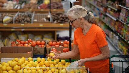 Slow motion view of smiling happy pretty mature woman selecting lemons in a grocery store.