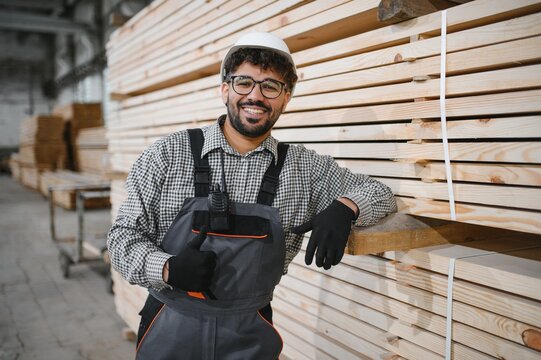 Arab carpenter gesturing thumbs up near lumber stacks in workshop