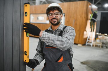 Arab construction worker using spirit level on modular house wall