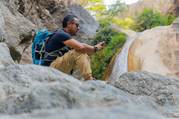 Hiker using smartphone near waterfall in puebla, mexico
