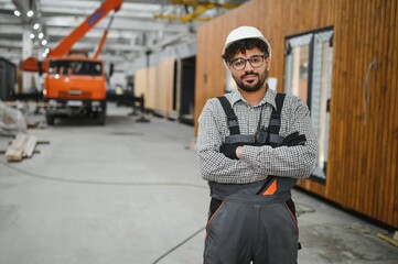 Arab construction worker posing with crossed arms in modular house production workshop