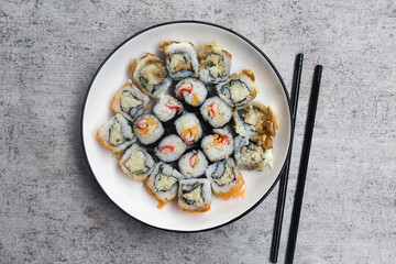 various kinds of sushi on a plate with chopsticks