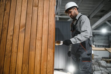Arab carpenter applying varnish on wooden planks in workshop