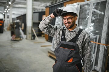 Smiling arab construction worker adjusting hardhat in modular house production workshop
