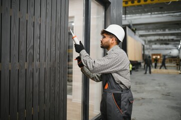 Construction worker applying sealant to prefabricated modular house