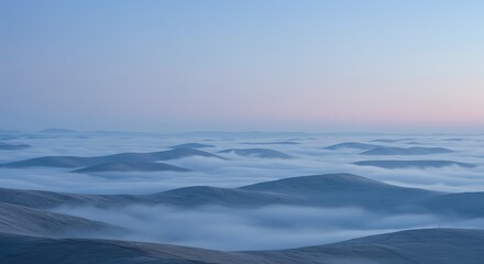 Obraz premium A mesmerizing view of rolling hills enveloped in a sea of mist under a serene sky. The soft hues of the sky create a sense of peace and tranquility, making this landscape a sight to behold.