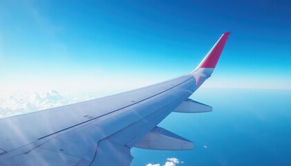 Fototapeta premium Airplane wing against blue sky, showcasing aerodynamic design, sky, wingspan