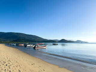 Serene beach in Paraty showcasing fishing boats and clear blue skies in Rio de Janeiro