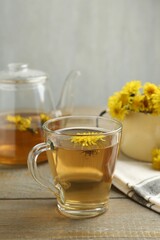 Refreshing dandelion tea and flowers on wooden table