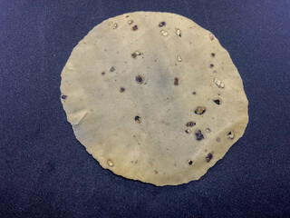 Raw, thin, crispy papad made from lentil flour and seasoned with black pepper. Indian snacks black background 
