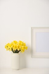 Beautiful daffodils in vase on white table at home
