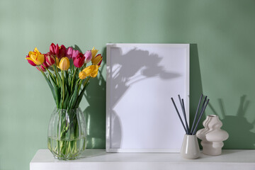 Bouquet of beautiful tulips and decor on table near color wall