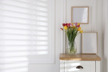 Bouquet of beautiful tulips and frame on wooden table indoors. Space for text