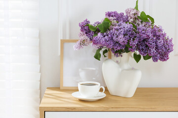 Bouquet of beautiful lilac flowers and coffee on wooden table. Space for text