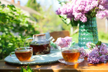 Beautiful lilac flowers, tea and zephyrs on wooden table in garden