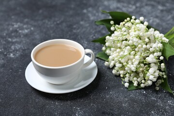 Bouquet of beautiful lily-of-the-valley flowers and coffee on black textured background, closeup