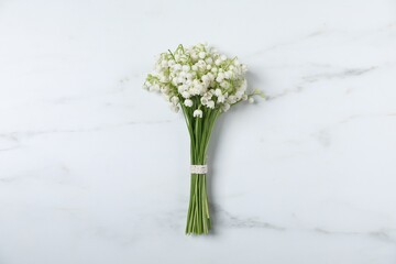 Bouquet of beautiful lily-of-the-valley flowers on white marble background, top view