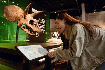 Two female friends standing and reading a sign, in a museum