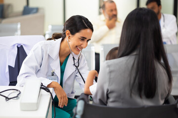 pediatrician : Hispanic Brazilian woman Doctor working with little asian boy patient and family at...
