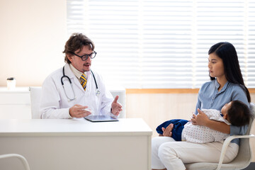 Fototapeta premium pediatrician : Hispanic or caucasian male Doctor working with little asian boy patient and family at hospital and wellness center.