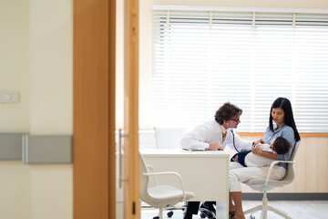 pediatrician : Hispanic or caucasian male Doctor working with little asian boy patient and family at hospital and wellness center.