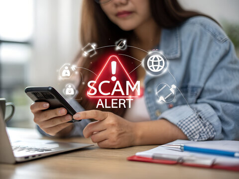 A person looks at a phone as a scam alert appears on the screen, they should be careful and avoid risky behavior.